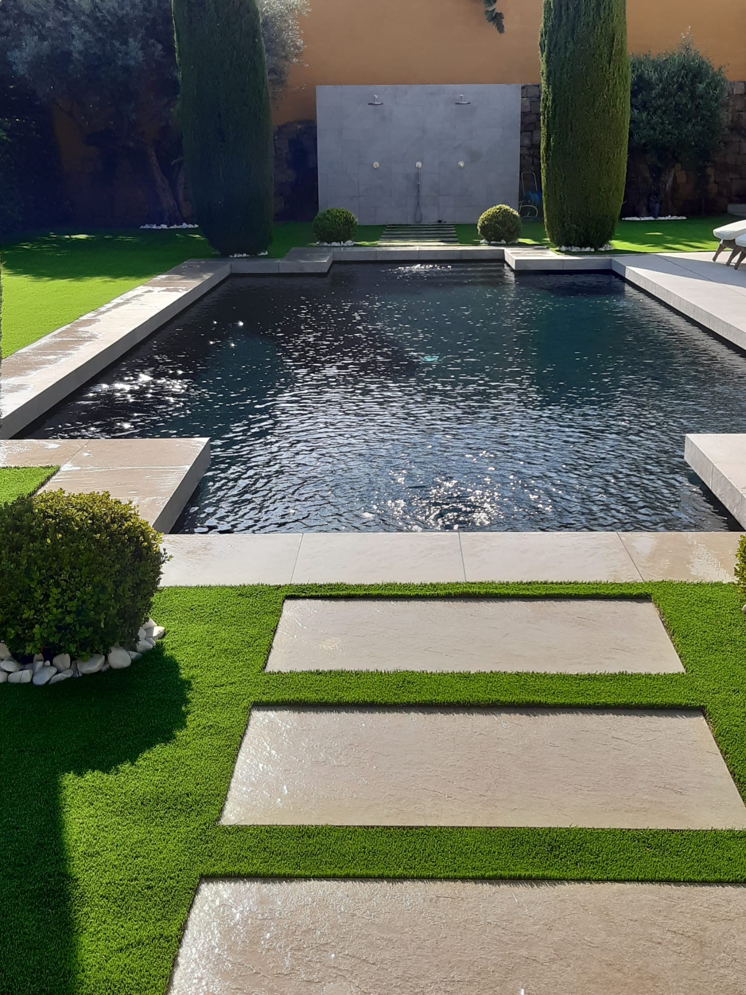 Dark luxury pool with artificial grass and stepping stones — SuperGrass Costa del Sol